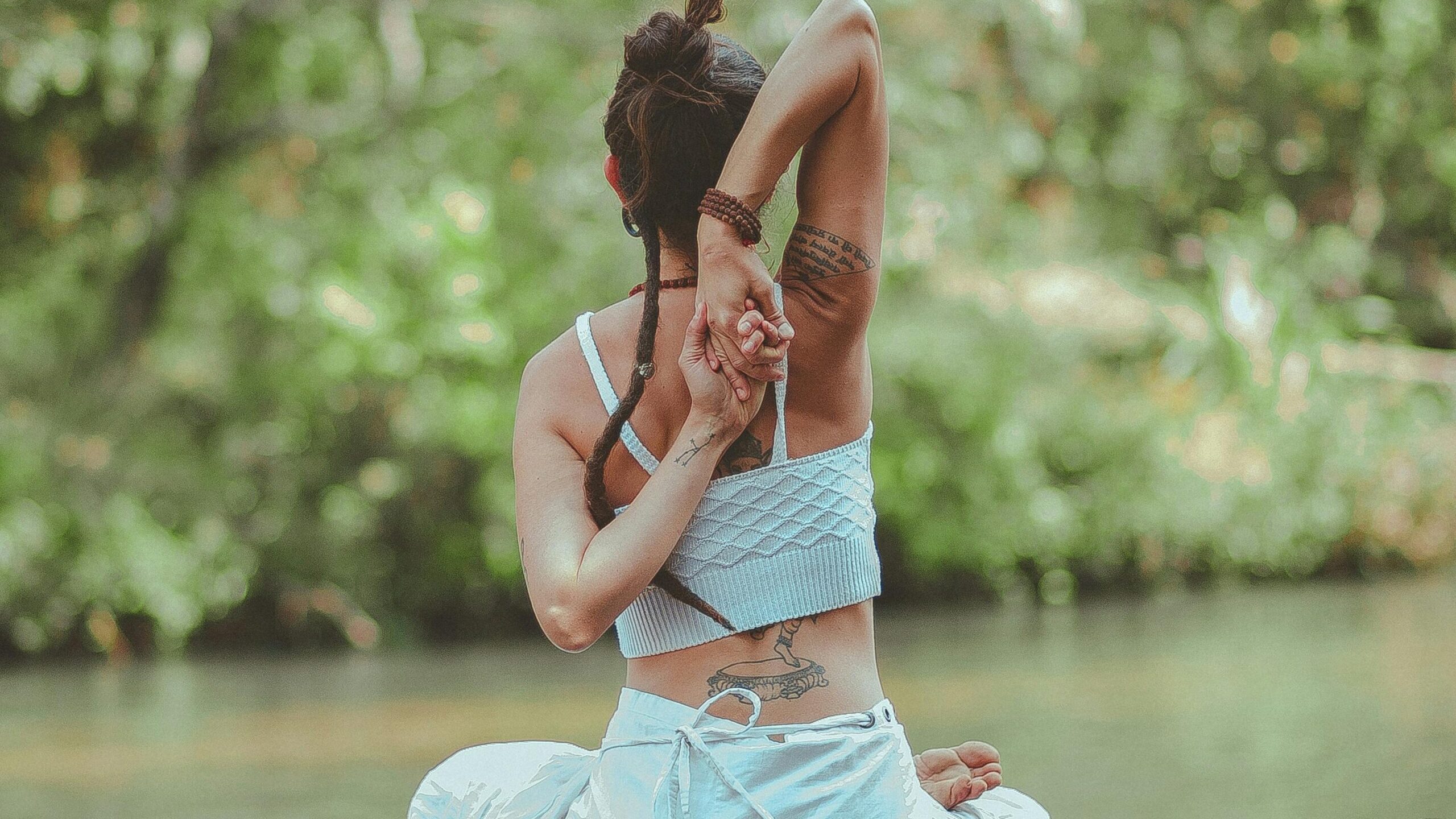 A woman in a yoga pose by a calm river, surrounded by nature, embodying peace and tranquility.